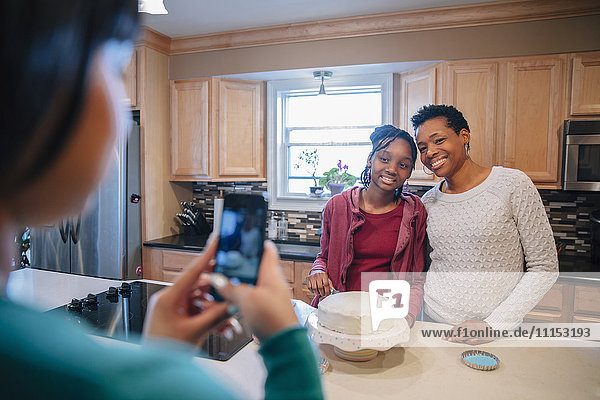 Schwarze Frau fotografiert Schwester und Mutter in der Küche