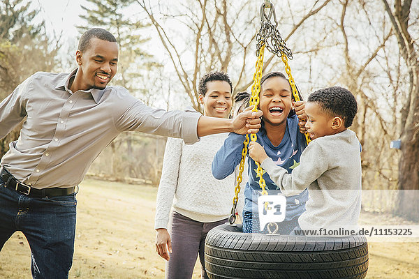 Black family playing on tire swing