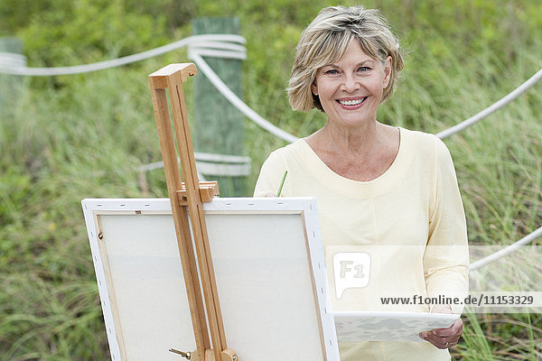 Older Caucasian woman painting outdoors