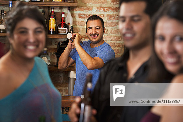 Hispanic bartender making drinks in bar