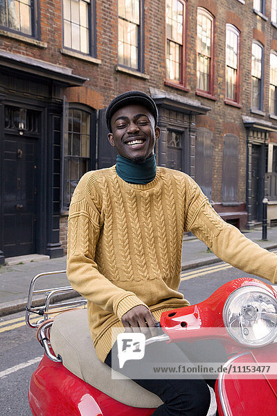 Black man riding scooter on urban street
