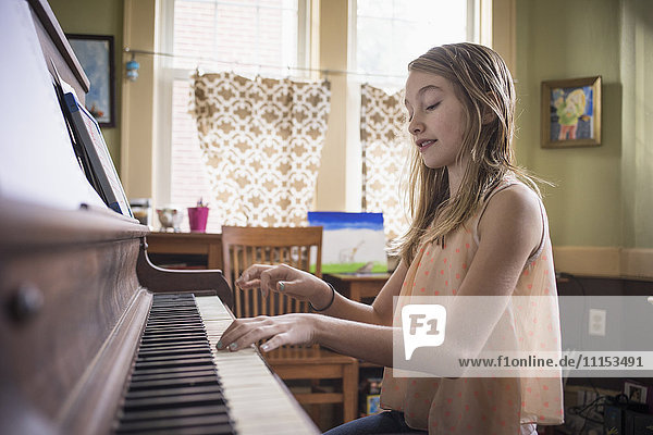 Kaukasisches Mädchen spielt Klavier im Wohnzimmer