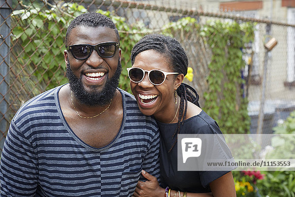 Lächelndes Paar mit Sonnenbrille in der Nähe des Zauns