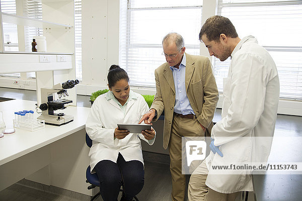 Businessman and scientists using digital tablet in laboratory