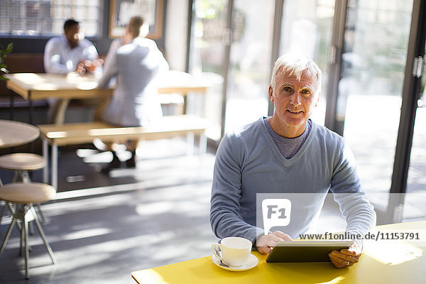 Älterer Mann benutzt digitales Tablet in einem Cafe