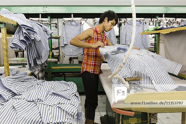 Asian worker ironing shirt in garment factory