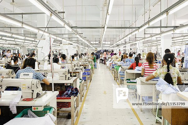 Asiatische Arbeiterin näht Kleidung in einer Bekleidungsfabrik
