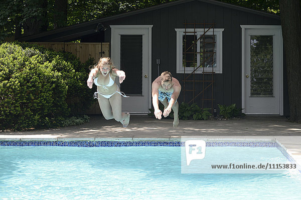 Paar taucht in den Swimmingpool im Hinterhof