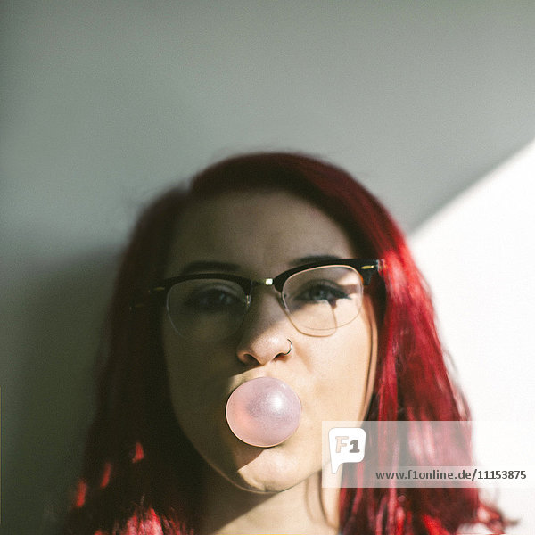 Caucasian woman blowing bubble gum bubble