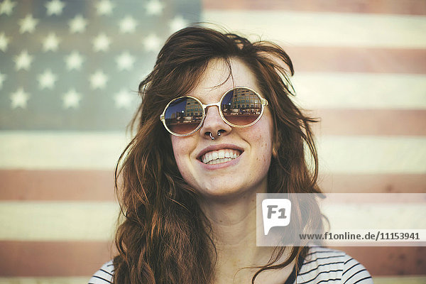 Caucasian woman wearing sunglasses at American flag