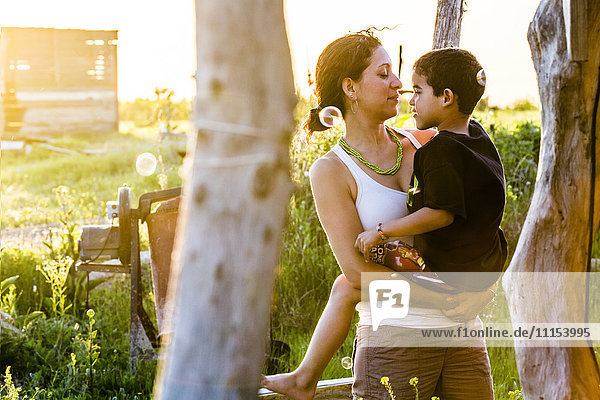 Hispanic mother carrying son in garden