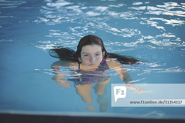 Kaukasisches Mädchen schwimmt im Schwimmbad