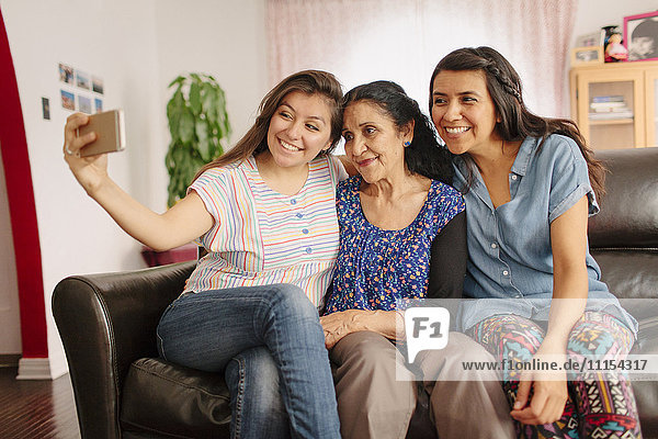 Großmutter und Enkeltöchter machen ein Selfie auf dem Sofa