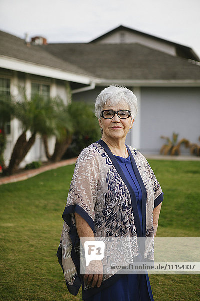 Ältere Frau steht im Hinterhof