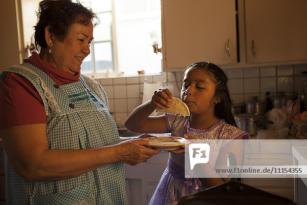 Hispanische Frau kocht für ihre Enkelin in der Küche