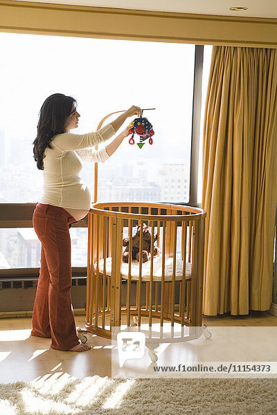 Schwangere Frau dekoriert Kinderzimmer