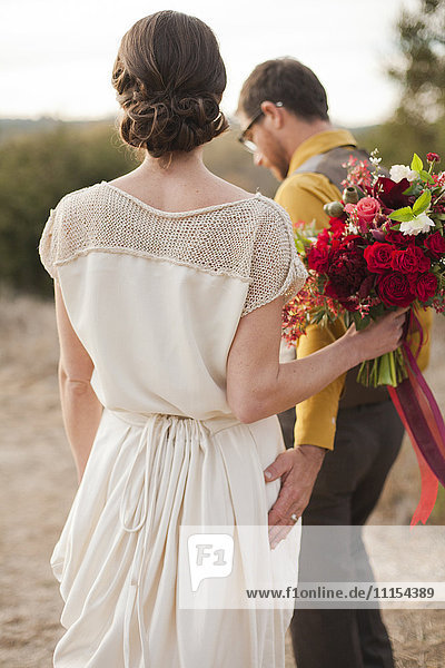 Braut und Bräutigam wandern auf einer ländlichen Anhöhe