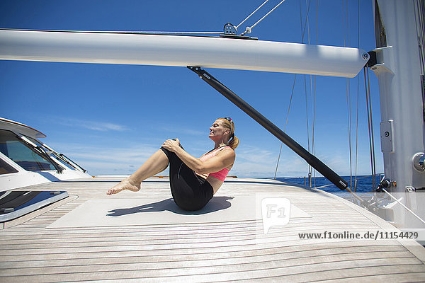 Kaukasische Frau übt Yoga auf dem Deck eines Segelboots