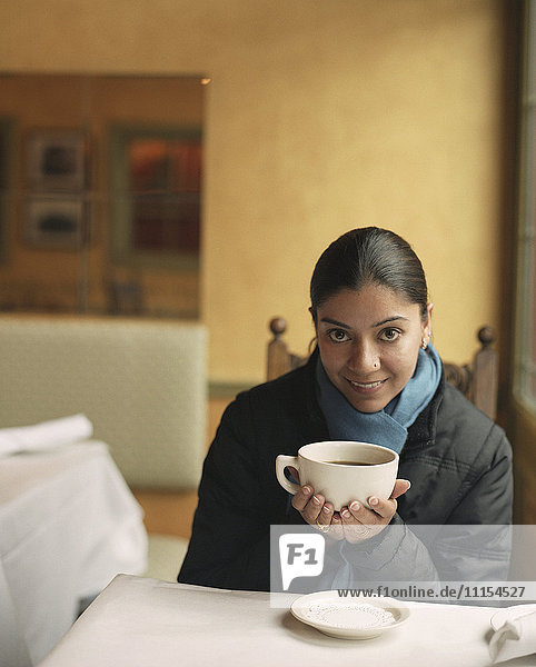 Indian woman drinking coffee in cafe