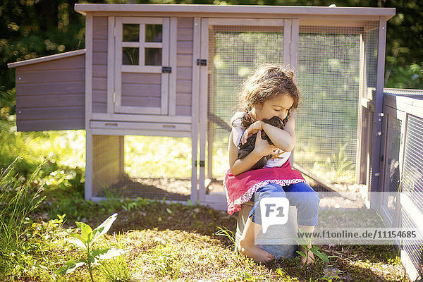 Mädchen umarmt Huhn im Bauernhof