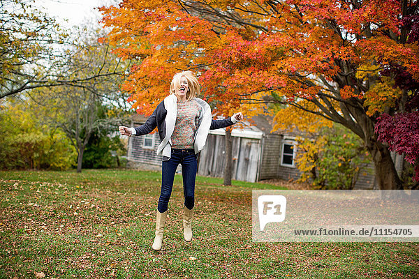 Caucasian woman jumping for joy in backyard