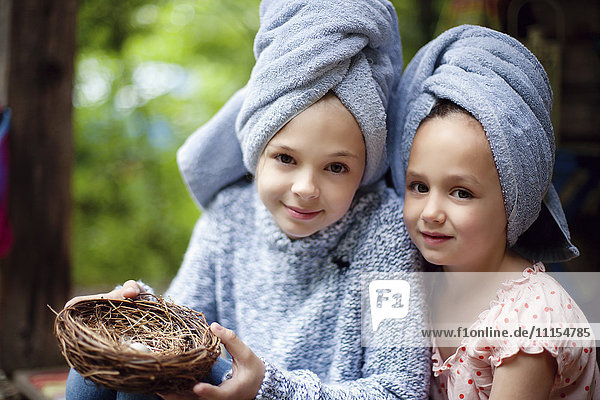 Caucasian sisters in hair towels holding bird nest
