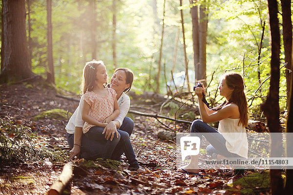 Kaukasisches Mädchen fotografiert Mutter und Schwester im Wald