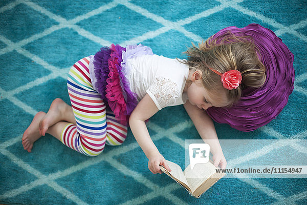 Mädchen liest Buch auf dem Boden