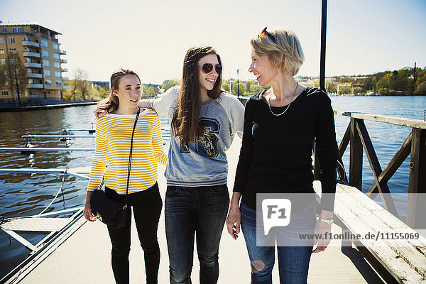 Mother and daughters walking on dock in harbor