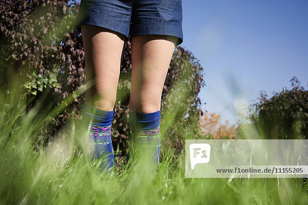 Frau in Shorts und Socken im hohen Gras