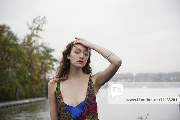 Pensive woman standing near lake