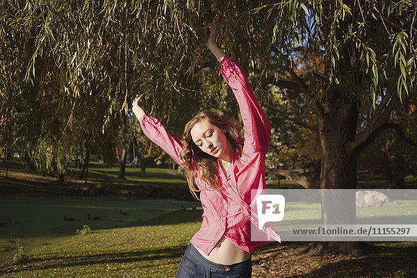 Woman dancing under tree in park