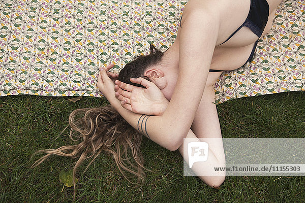 Frau sonnt sich im Bikini auf einer Decke im Gras