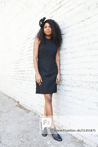 Stilvolle schwarze Frau lehnt sich an eine Backsteinmauer