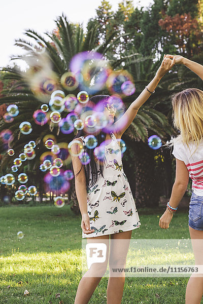 Weibliche Freunde haben Spaß mit Seifenblasen im Park