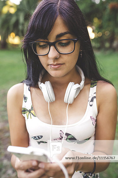 Junge Frau mit Kopfhörer beim Blick aufs Handy