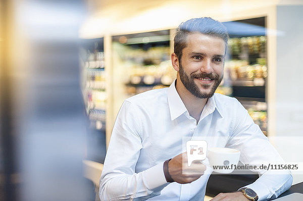 Lächelnder Geschäftsmann mit einer Tasse Kaffee im Cafe
