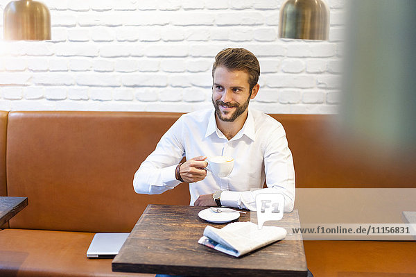 Lächelnder Geschäftsmann sitzend in einem Café mit einer Tasse Kaffee