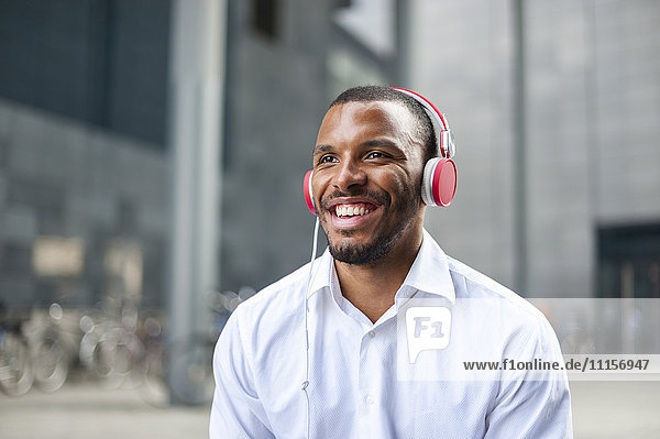 Portait of happy businessman listening music with headphones