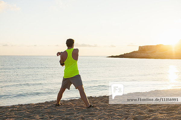 Spanien  Mallorca  Jogger am Strand am Morgen  Stretching