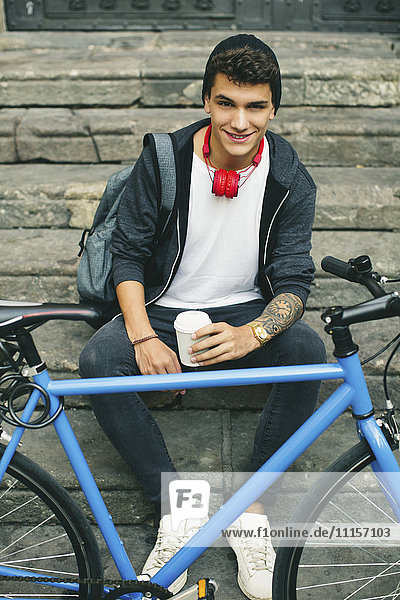 Teenager with a fixie bike sitting on steps  coffee to go  smiling