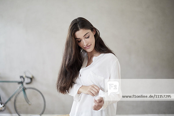 Young woman rolling up sleeve of her blouse
