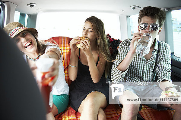 Three teenage friends having a snack in car