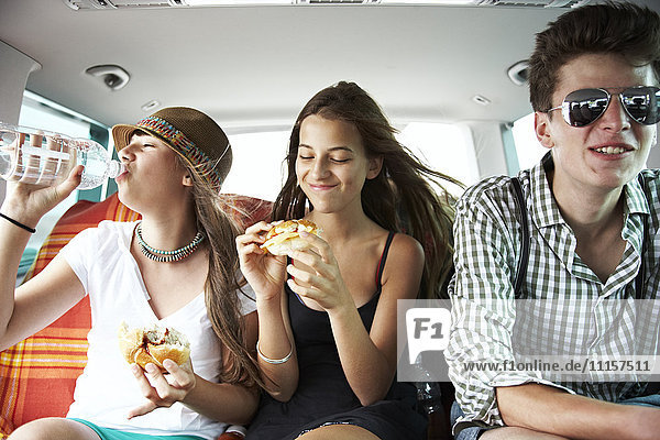 Drei Teenager-Freunde bei einem Snack im Auto