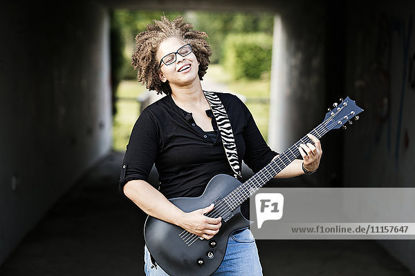Glückliche Frau beim Gitarrespielen