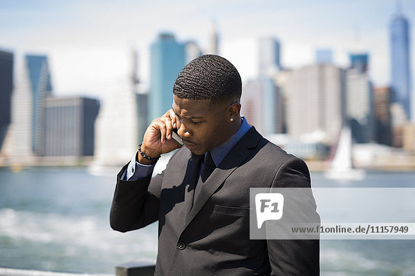 USA  Brooklyn  businessman on the phone in front of Manhattan skyline