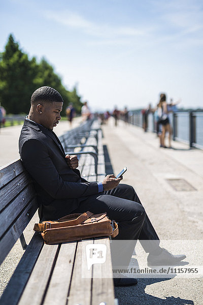 Businessman sitting on bench looking at cell phone