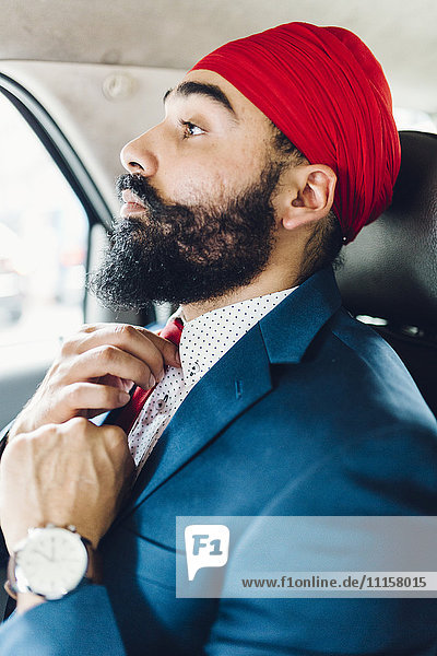 Indischer Geschäftsmann bindet Krawatte in einem Taxi