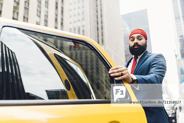 Indischer Geschäftsmann in Manhattan beim Einsteigen in ein gelbes Taxi