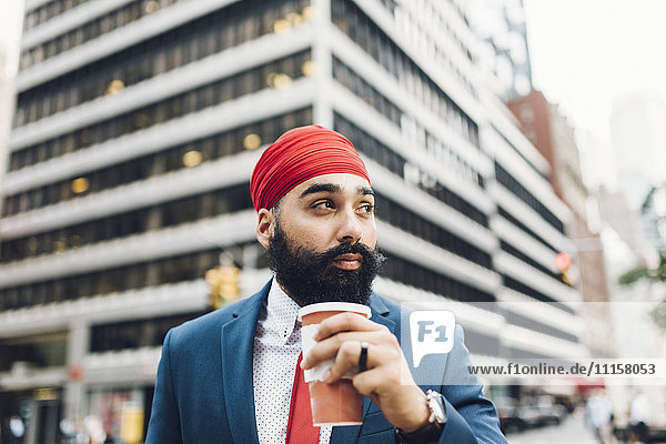 Indischer Geschäftsmann  der in Manhattan spazieren geht und Kaffee trinkt.